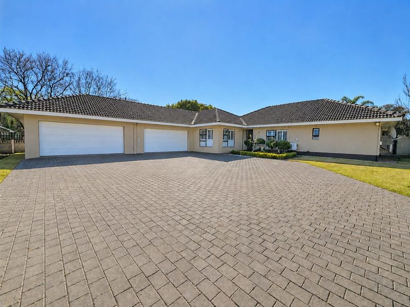 Spacious front exterior view of a well-maintained single-story house featuring a large paved driveway and a double garage.