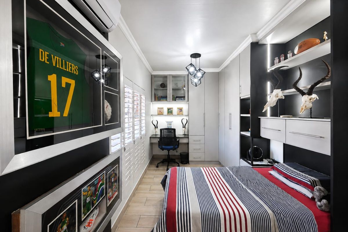 Modern bedroom featuring extensive built-in cabinetry, a dedicated study nook, plantation shutters, and high-quality tiled flooring with integrated lighting.