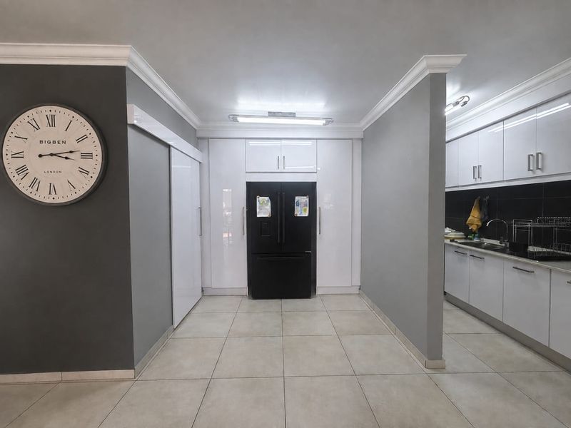 Modern kitchen featuring high-gloss white cabinetry, tiled flooring, and a dedicated integrated refrigerator space with a clean, contemporary aesthetic.