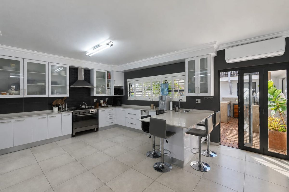 Modern kitchen featuring white cabinetry, stone countertops, a gas stove, and direct access to an outdoor patio area.