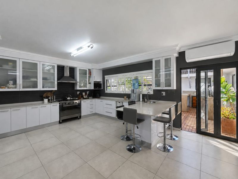 Modern kitchen featuring white cabinetry, stone countertops, a gas stove, and direct access to an outdoor patio area.