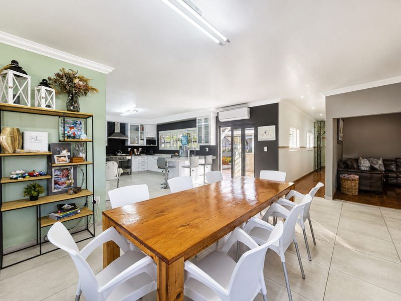 Spacious open-plan dining and kitchen area featuring tiled floors, modern cabinetry, a central island, and direct access to the outdoor patio.