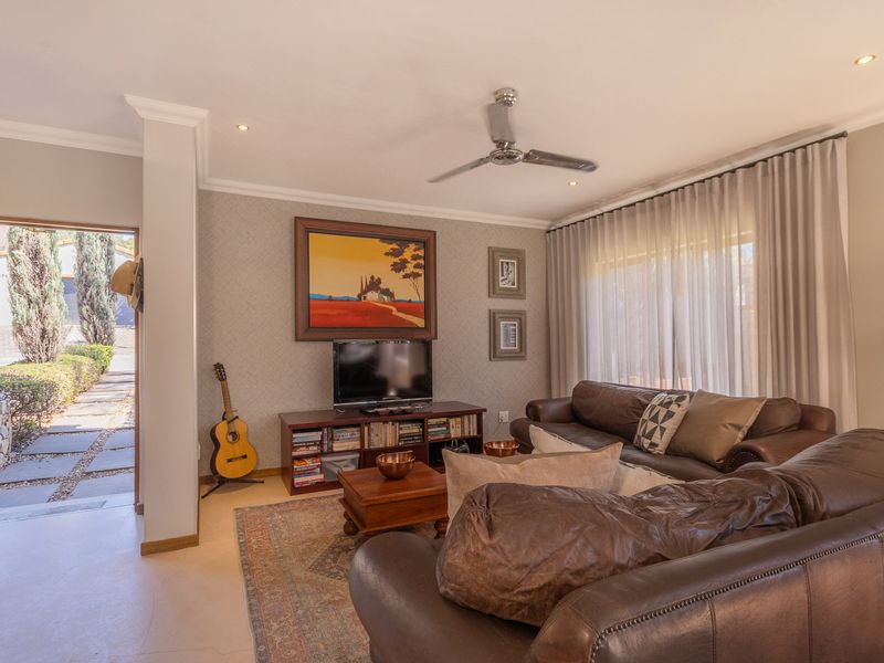 A well-maintained living room featuring recessed lighting, a ceiling fan, and textured wallpaper, with direct access to an outdoor patio area.