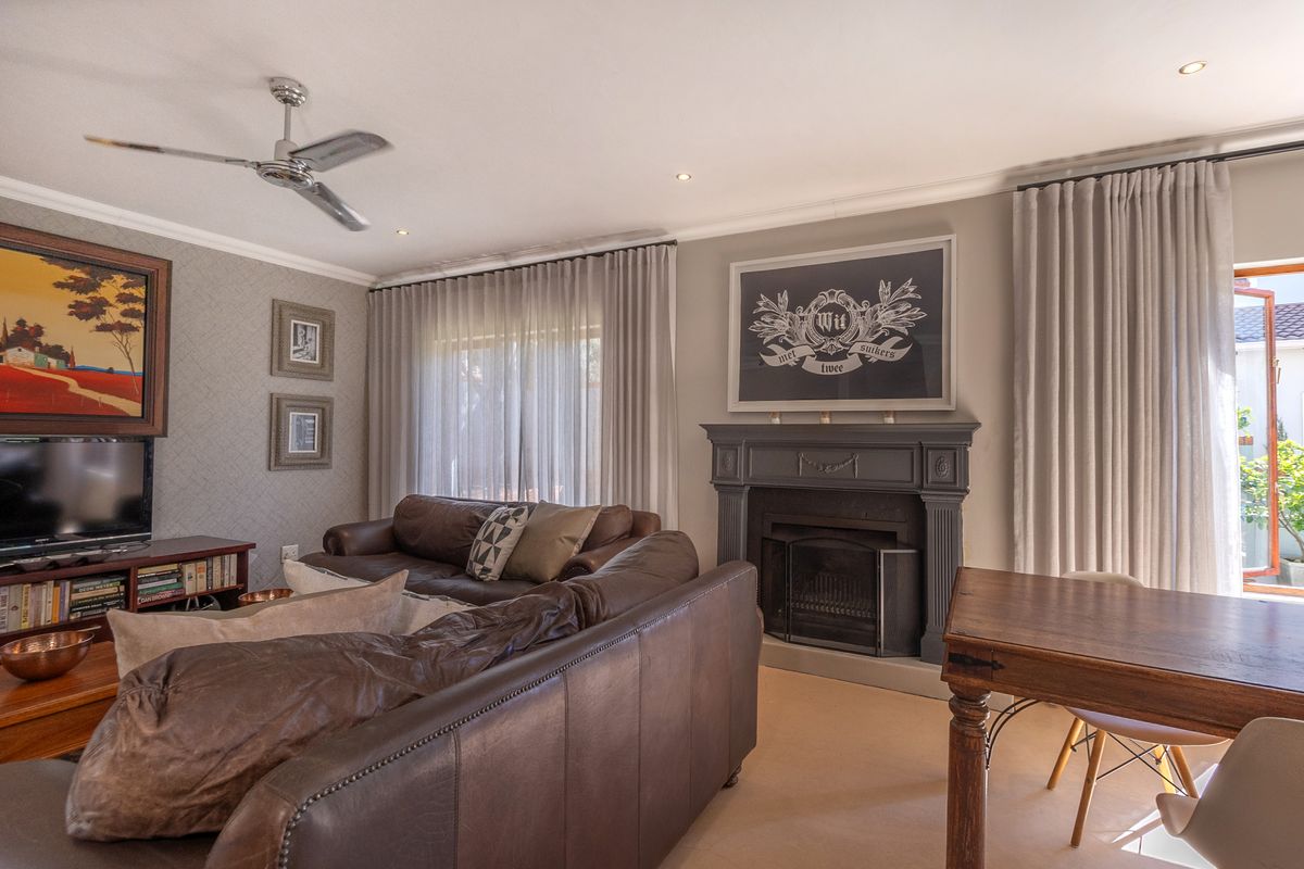 A well-maintained living room featuring a classic fireplace, ceiling fan, recessed lighting, and large glass sliding doors leading to the exterior.