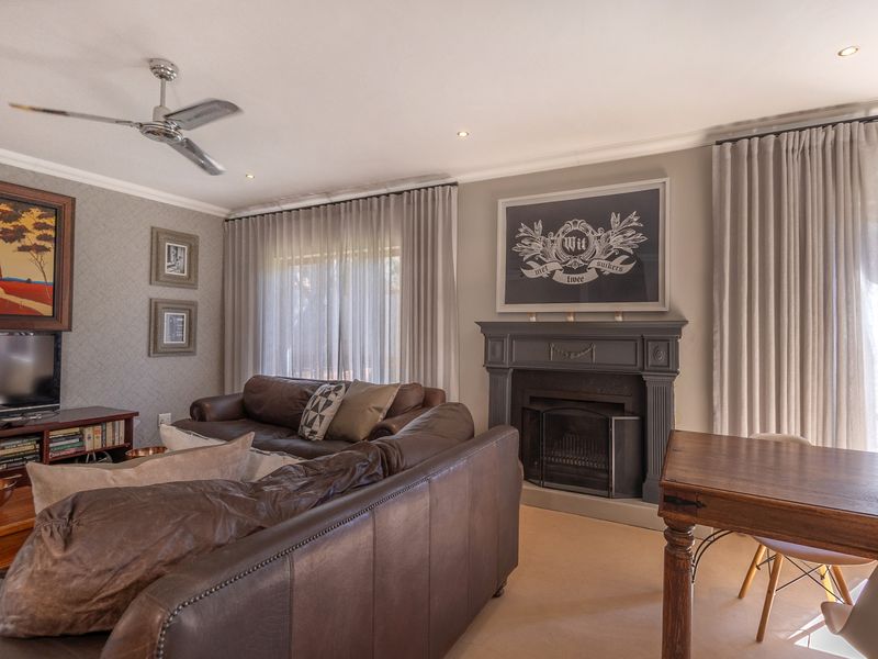 A well-maintained living room featuring a classic fireplace, ceiling fan, recessed lighting, and large glass sliding doors leading to the exterior.