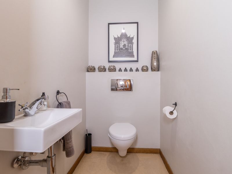 A clean and modern guest cloakroom featuring a wall-mounted toilet with a chrome flush plate and a sleek wall-mounted basin.