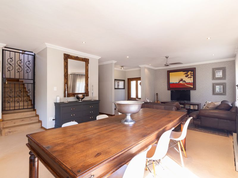 Spacious open-plan living and dining area featuring a fireplace, recessed lighting, and a distinctive wrought iron staircase railing.
