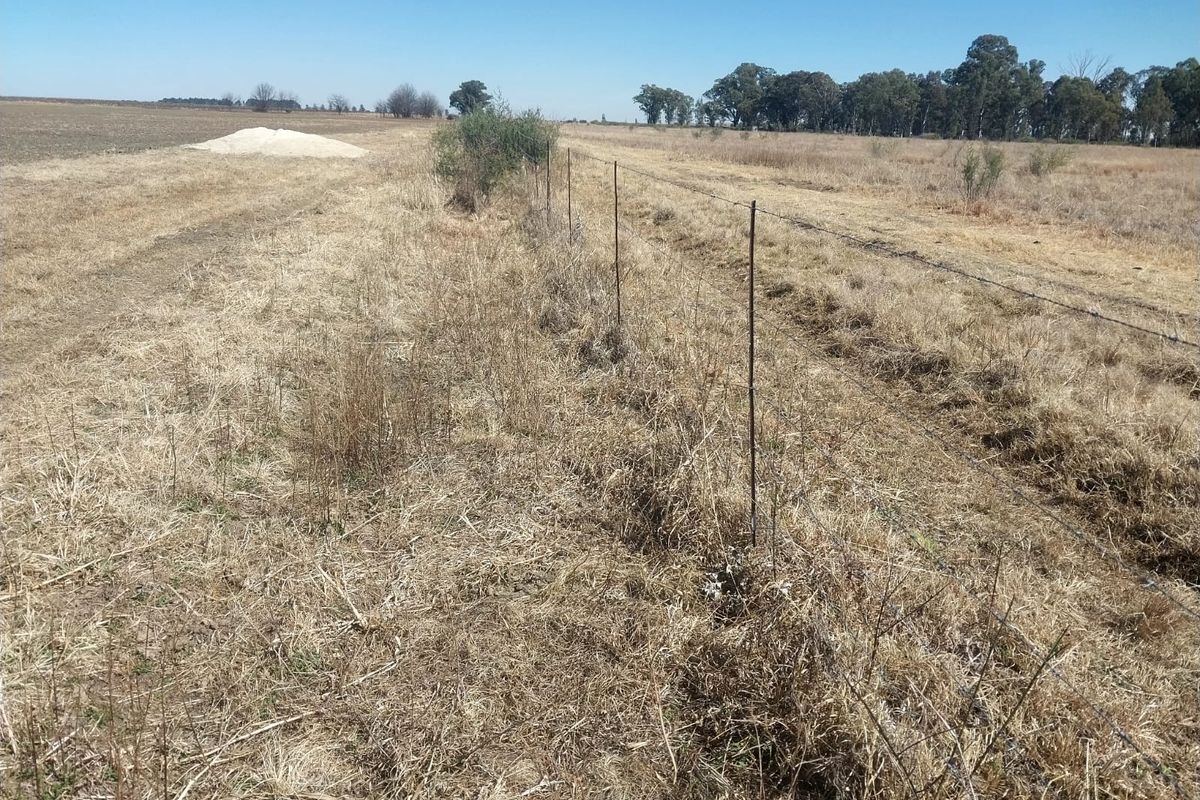 A view of the expansive farm land featuring a simple barbed wire fence boundary line.