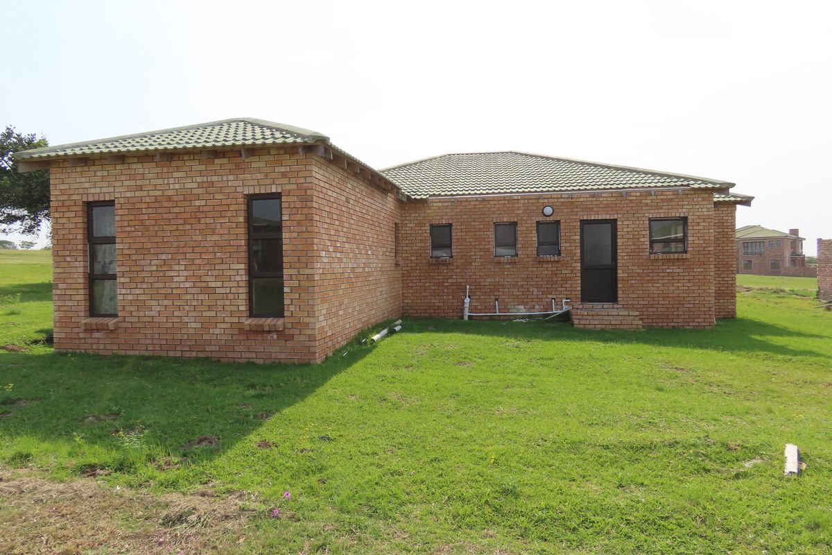 Rear view of a face brick house featuring a tiled roof and aluminium window frames, set on a grassed plot.