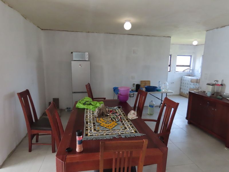 Open plan living and dining area featuring tiled flooring and basic lighting, currently requiring finishing touches to wall and ceiling joints.