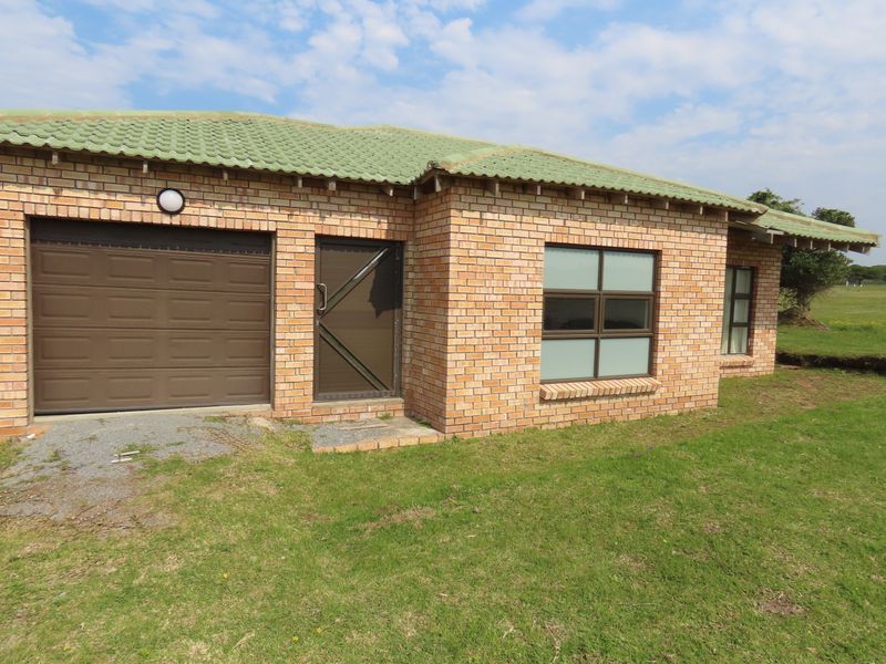 Exterior view of a face brick house featuring a tiled roof, integrated garage, and aluminium window frames set on a grassed plot.