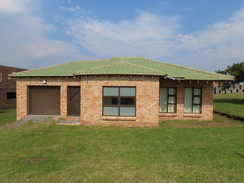 A single-story face brick house featuring a tiled roof, integrated single garage, and aluminium window frames, set on a spacious grassed plot.
