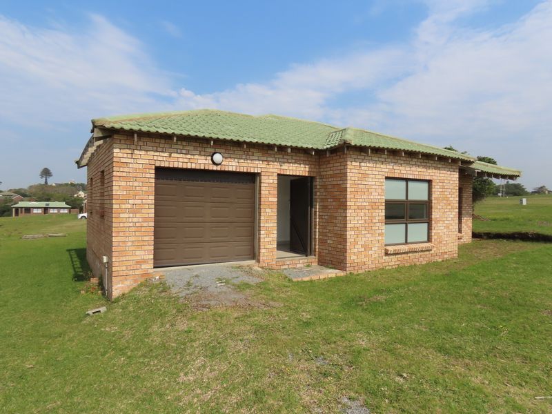 A detached face brick structure featuring a tiled roof, a single sectional garage door, and aluminium window frames, set within an open grassed area.