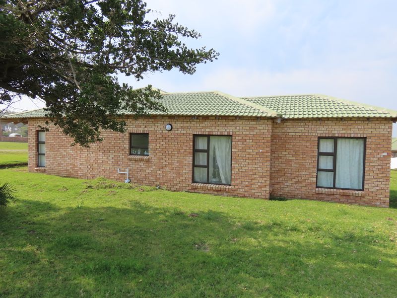 A view of the rear exterior of the house featuring face brick walls, a tiled roof, and aluminium-framed windows set against a lawn.