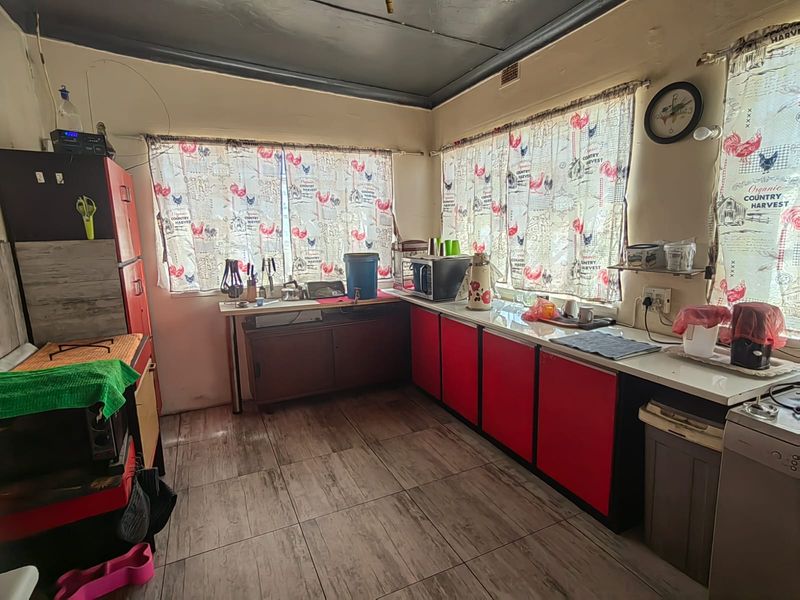 A functional kitchen featuring tiled flooring, fitted cabinetry, and ample counter space, offering potential for modernization and aesthetic updates.