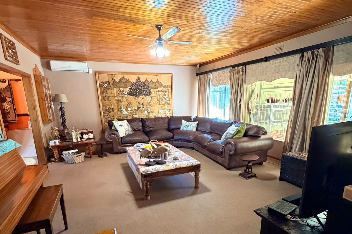 Spacious living room featuring a warm timber tongue and groove ceiling, ceiling fan, and split system air conditioning for year-round comfort.