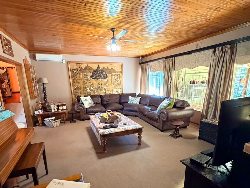 Spacious living room featuring a warm timber tongue and groove ceiling, ceiling fan, and split system air conditioning for year-round comfort.