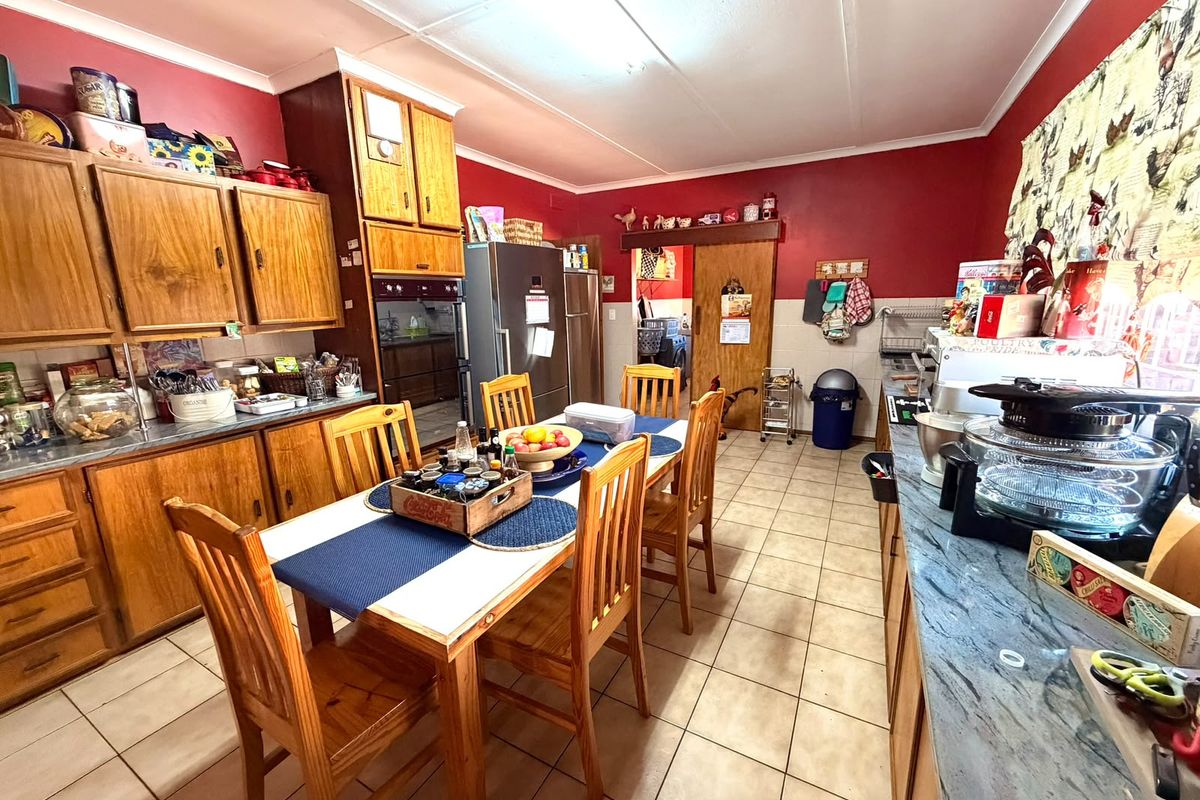 A dated kitchen featuring wooden cabinetry, tiled flooring, and laminate countertops, offering a functional layout with potential for modern renovation and aesthetic updates.
