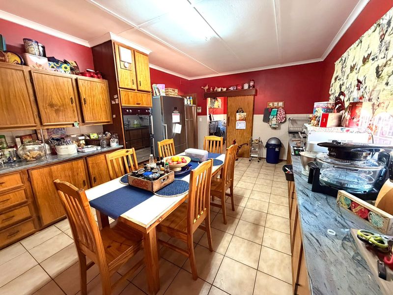 A dated kitchen featuring wooden cabinetry, tiled flooring, and laminate countertops, offering a functional layout with potential for modern renovation and aesthetic updates.
