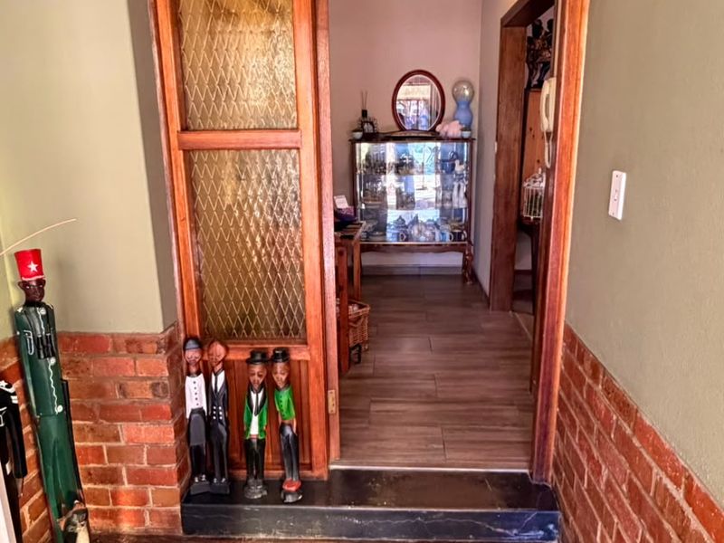 Entrance foyer featuring rustic stone flooring, exposed brick wall accents, and a timber-framed door with textured glass detailing.