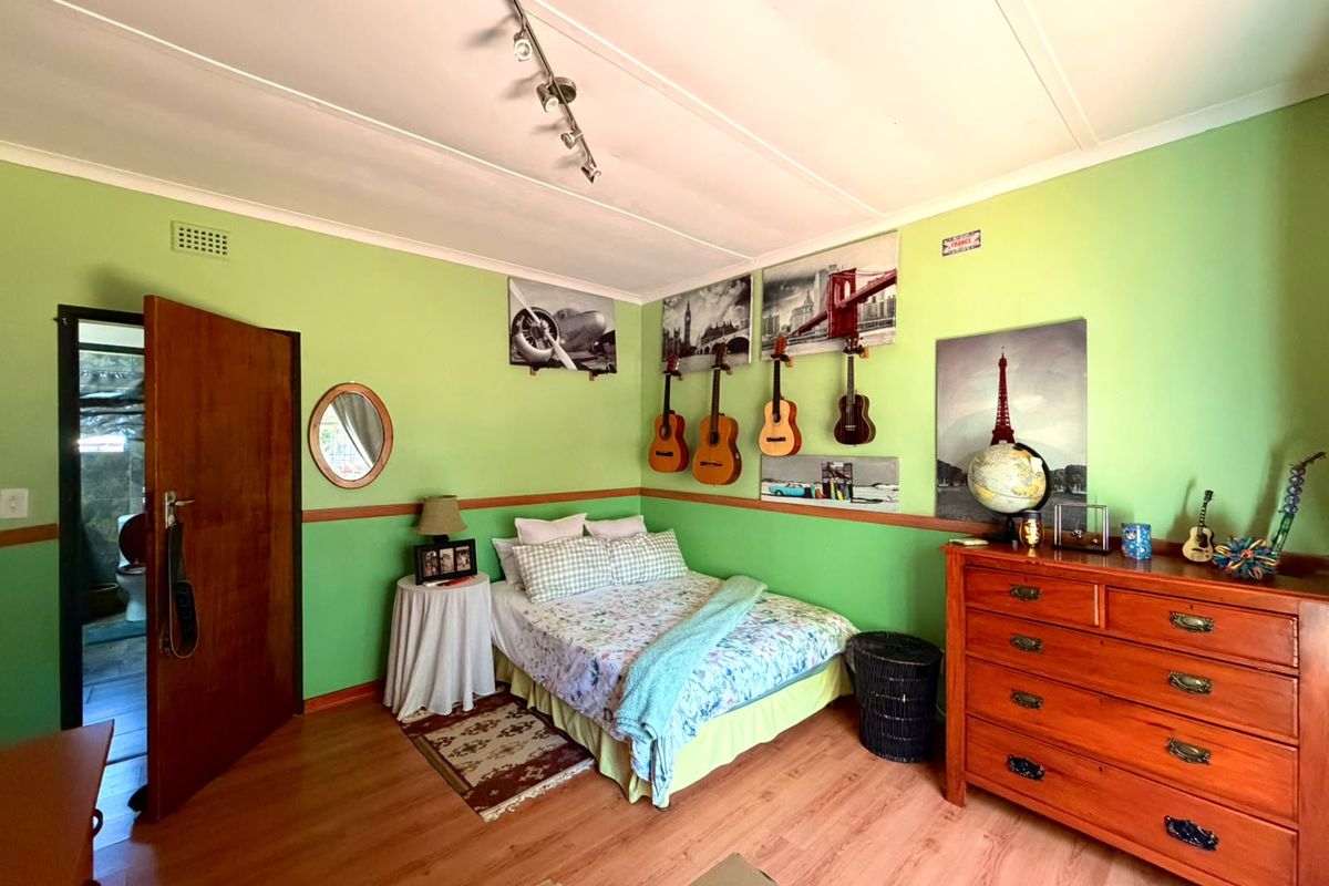 A bedroom featuring laminate flooring, track lighting, and a chair rail, with a view into an adjacent bathroom.