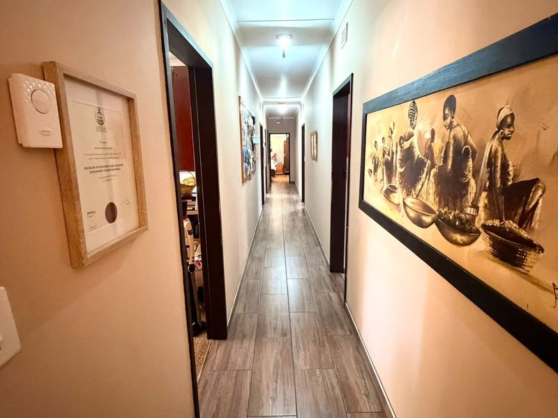 A long, well-maintained hallway featuring wood-look tile flooring and neutral wall finishes, providing access to multiple rooms.