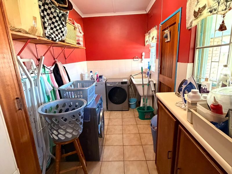 A functional laundry room featuring tiled flooring, built-in cabinetry, and a utility sink, providing essential space for washing and storage needs.