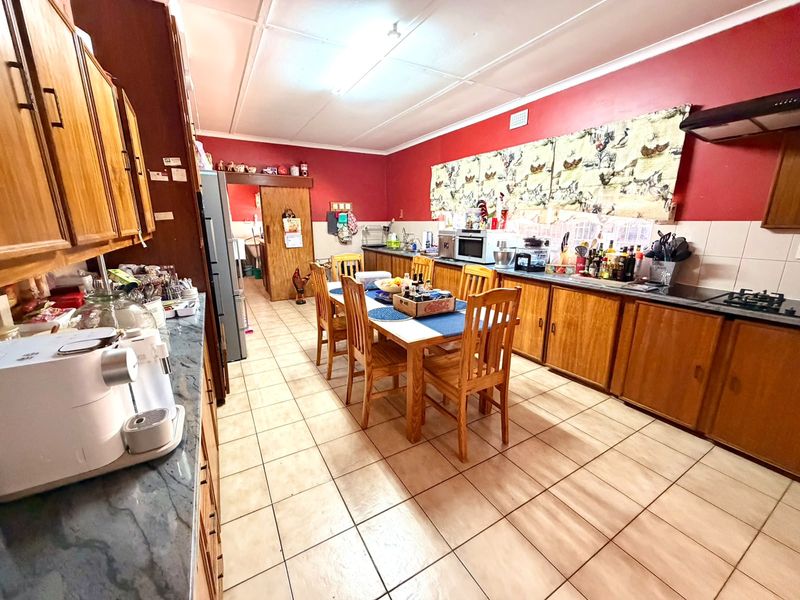 Spacious open-plan kitchen and dining area featuring wooden cabinetry, tiled flooring, and a functional layout with built-in cooking appliances.