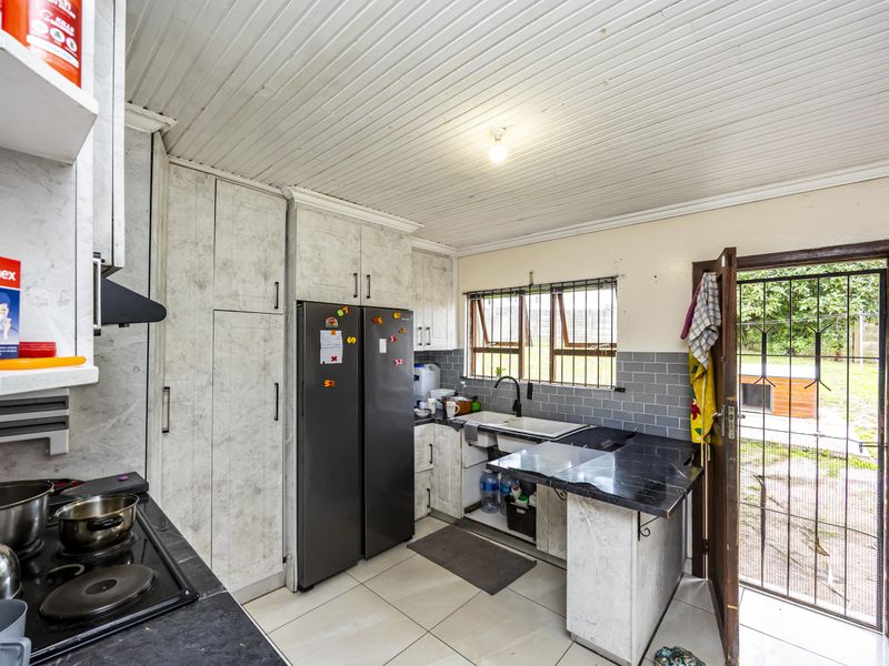 Functional kitchen featuring built-in cabinetry, black stone countertops, and direct access to the rear garden through a security gate.