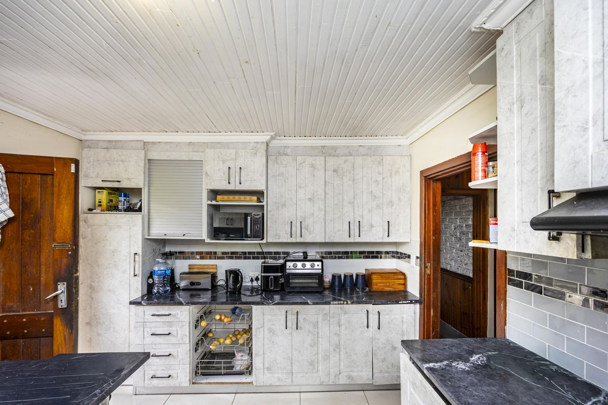 A functional kitchen featuring stone-look laminate cabinetry, tiled backsplash, and a tongue and groove ceiling, offering potential for a modern cosmetic update.