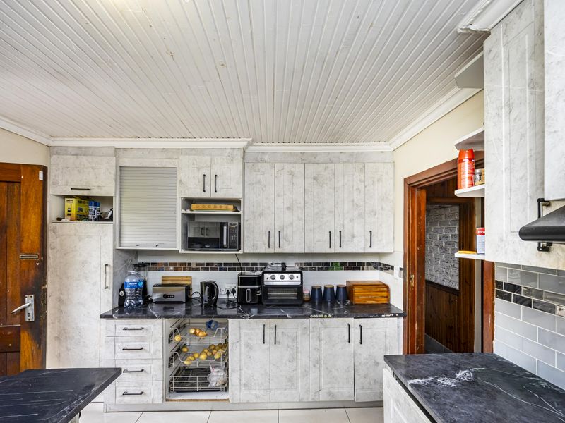 A functional kitchen featuring stone-look laminate cabinetry, tiled backsplash, and a tongue and groove ceiling, offering potential for a modern cosmetic update.