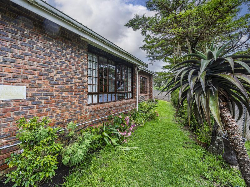 A view of the rear exterior of the townhouse, featuring a classic face brick facade, timber-framed windows, and a well-maintained garden area.