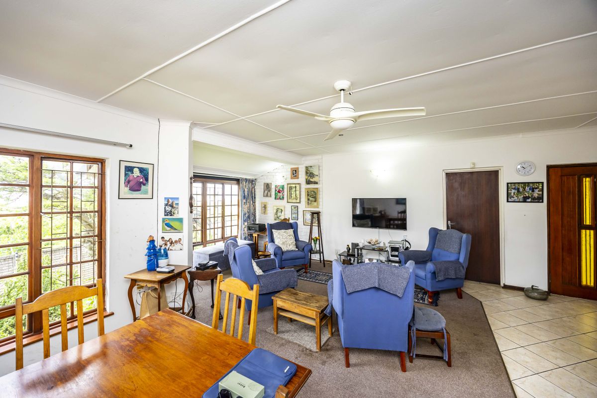 Spacious living area featuring a ceiling fan, mixed flooring, and timber window frames, offering a functional layout with potential for modernization.