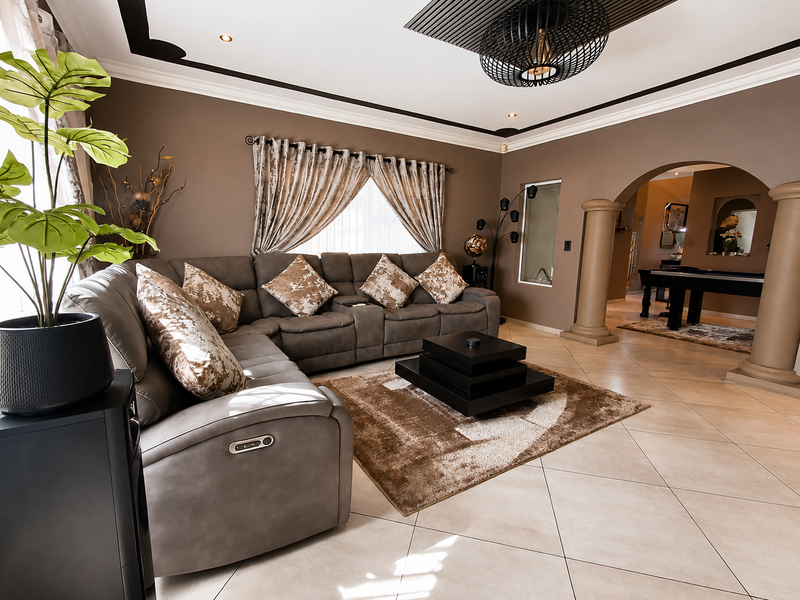 Spacious living room featuring tiled flooring, decorative columns, an arched entryway, and recessed ceiling lighting with modern architectural detailing.