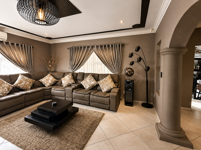 A well-maintained living room featuring tiled flooring, decorative ceiling molding, and a prominent architectural archway with a column.