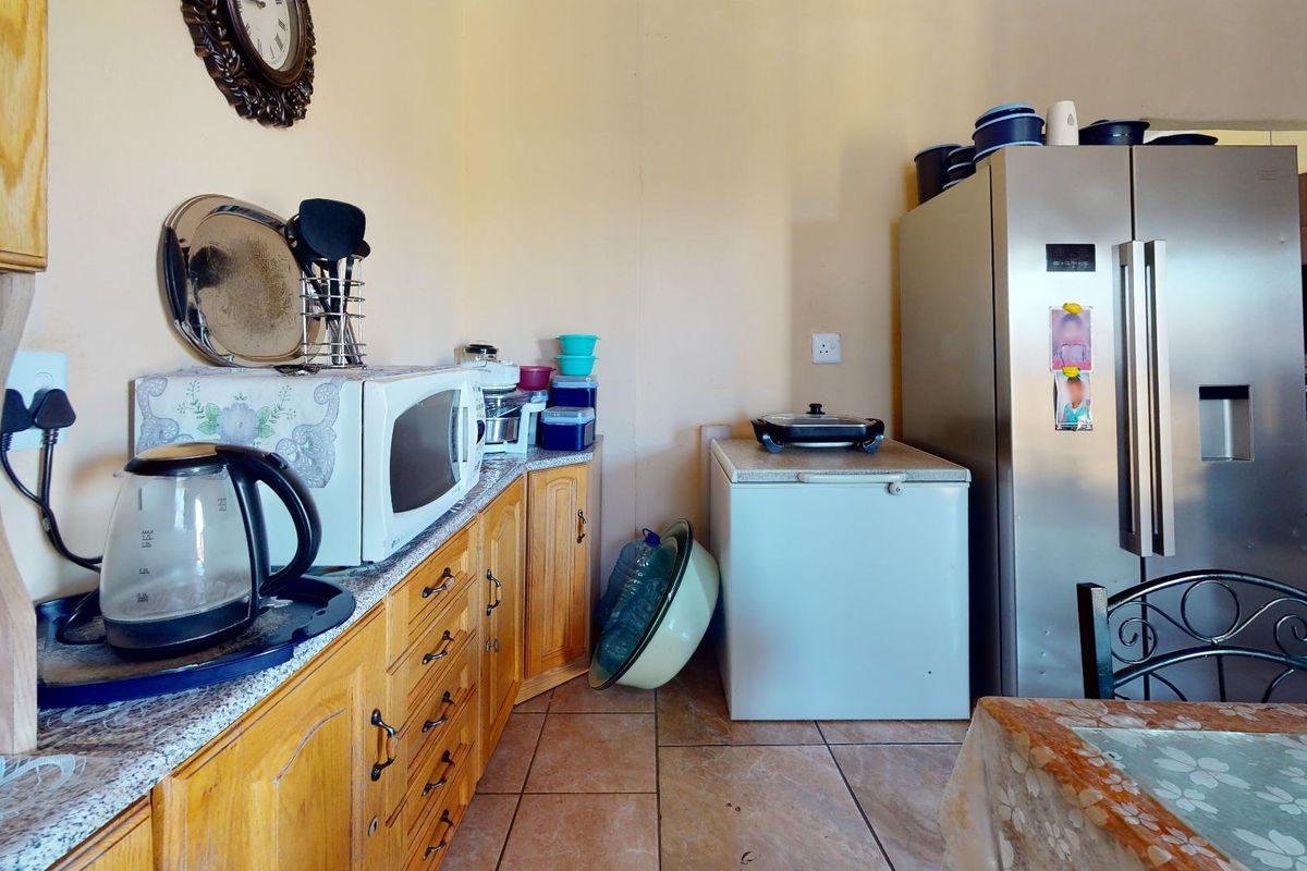 A functional kitchen area featuring wooden cabinetry, tiled flooring, and space for large appliances.