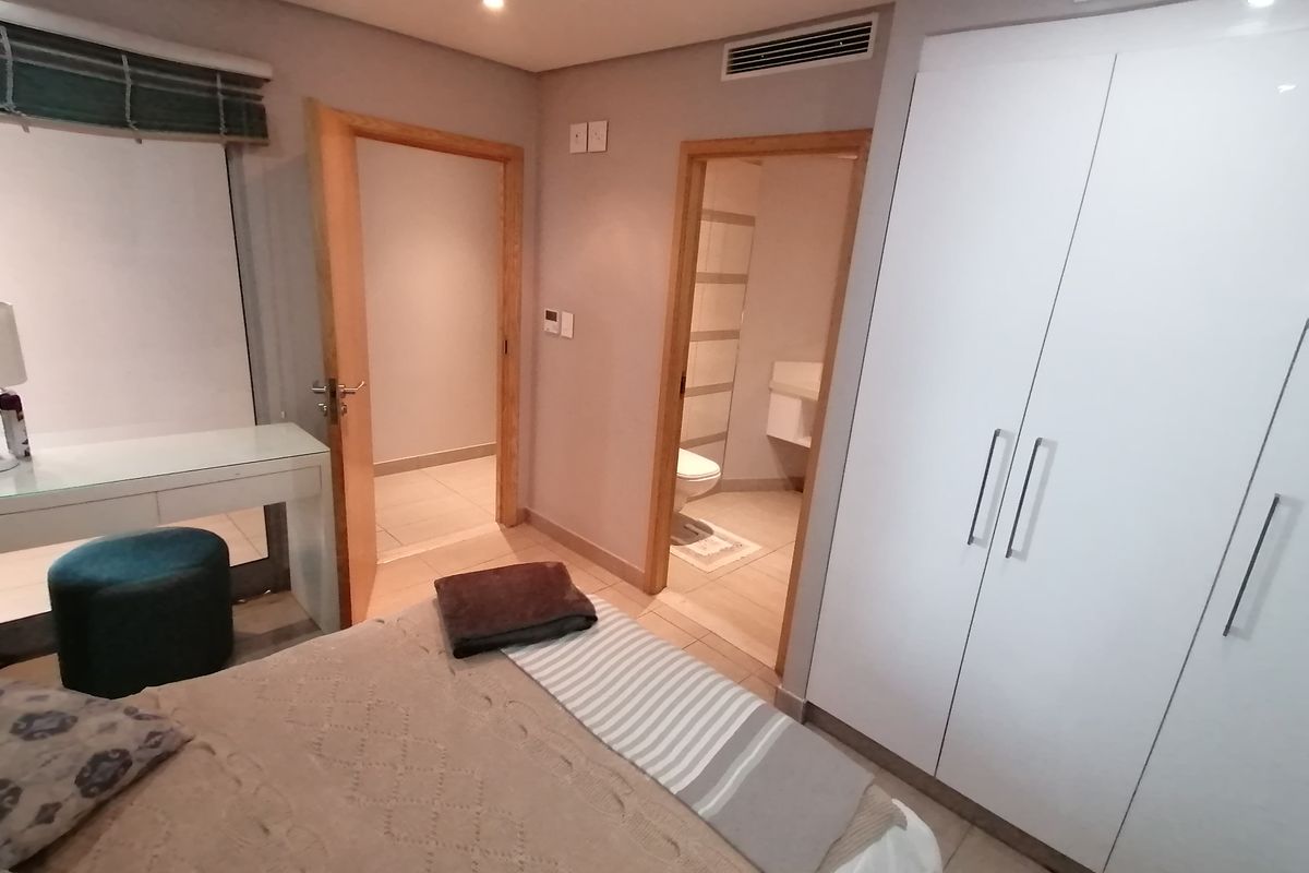 A well-maintained bedroom featuring built-in wardrobes, tiled flooring, ducted air conditioning, and direct access to an en-suite bathroom.