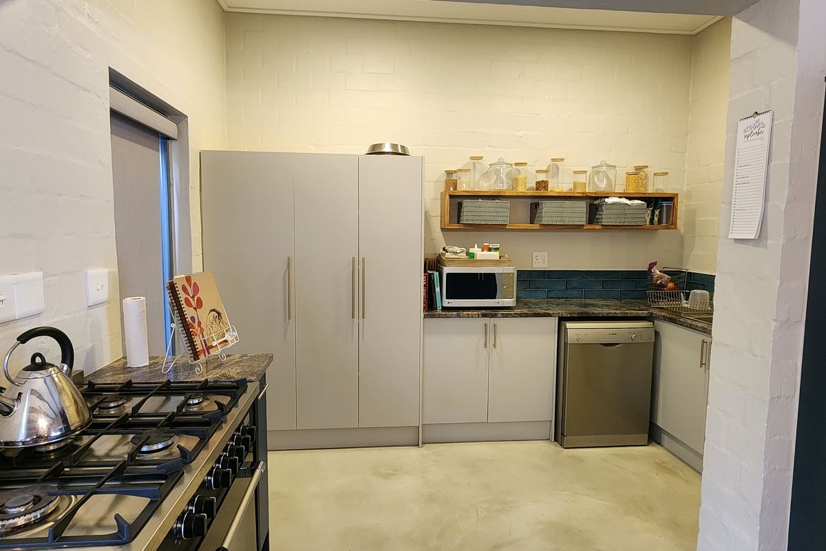 A functional kitchen featuring built-in cabinetry, a gas hob, integrated dishwasher space, and a tiled backsplash with a polished concrete floor.