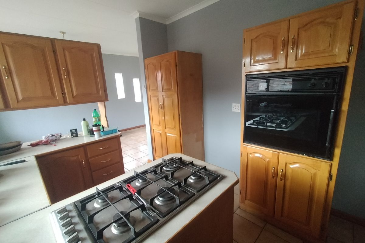 A functional kitchen featuring traditional wooden cabinetry, a central island with a gas hob, and a built-in wall oven.