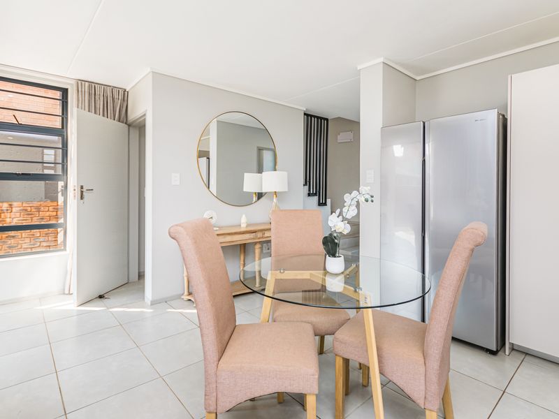Bright open-plan living area featuring neutral tiled flooring, large aluminium-framed windows, and built-in storage cabinetry.