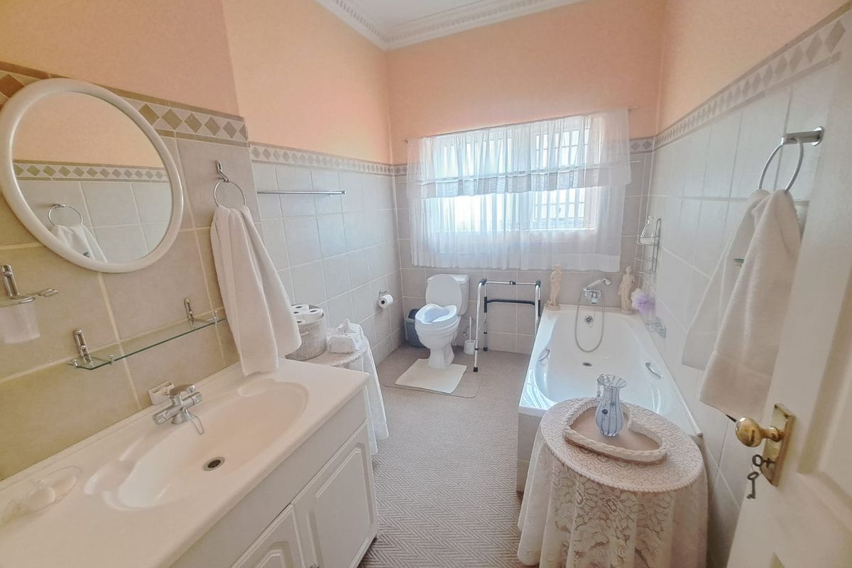 A functional bathroom featuring a built-in bathtub, vanity cabinet with basin, and toilet, finished with neutral wall tiles and classic crown molding.