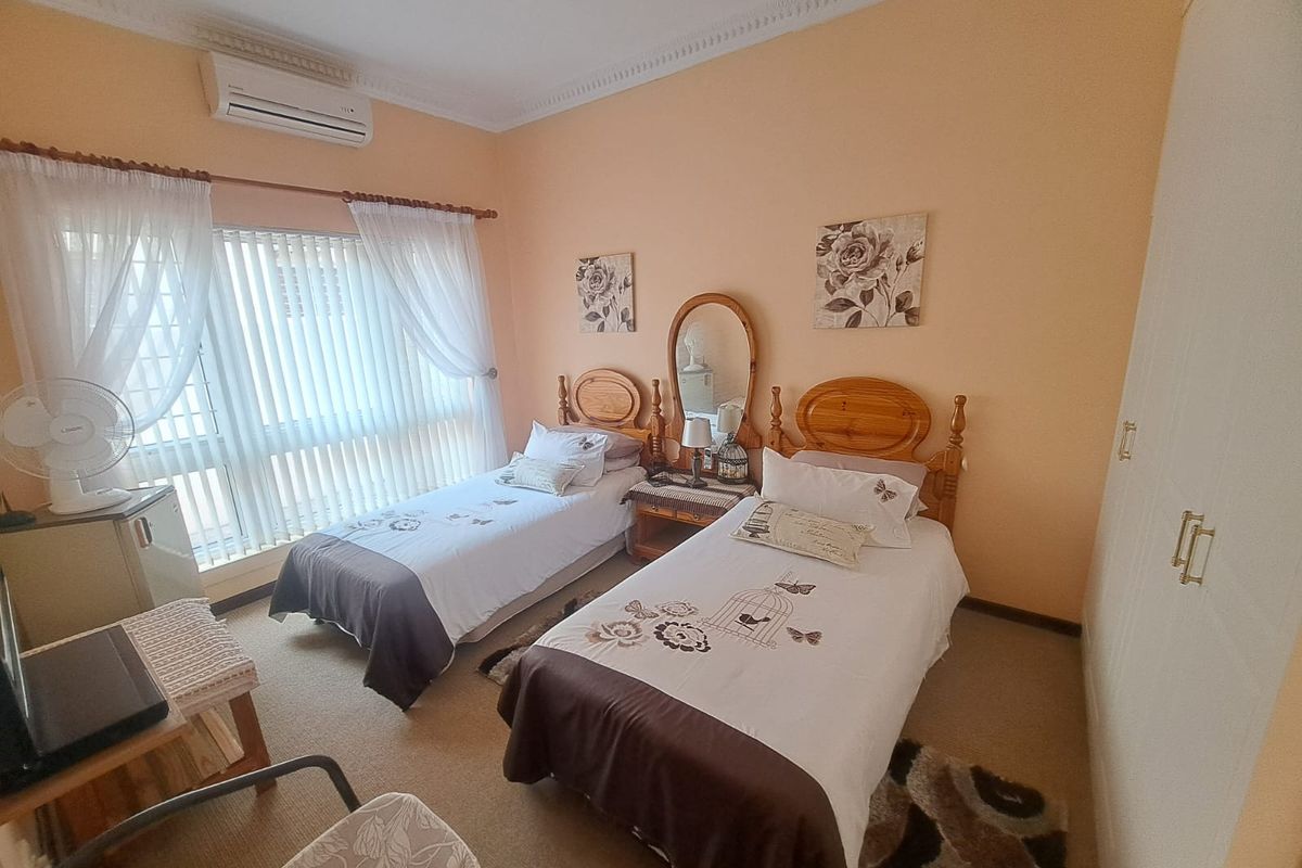 A well-maintained bedroom featuring built-in cupboards, an air conditioning unit, and decorative cornice detailing, offering a comfortable and functional living space.