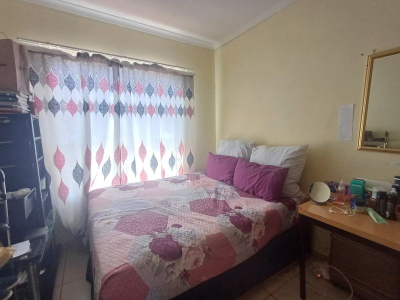A standard bedroom featuring tiled flooring and a window with curtains, providing a functional space for rest.