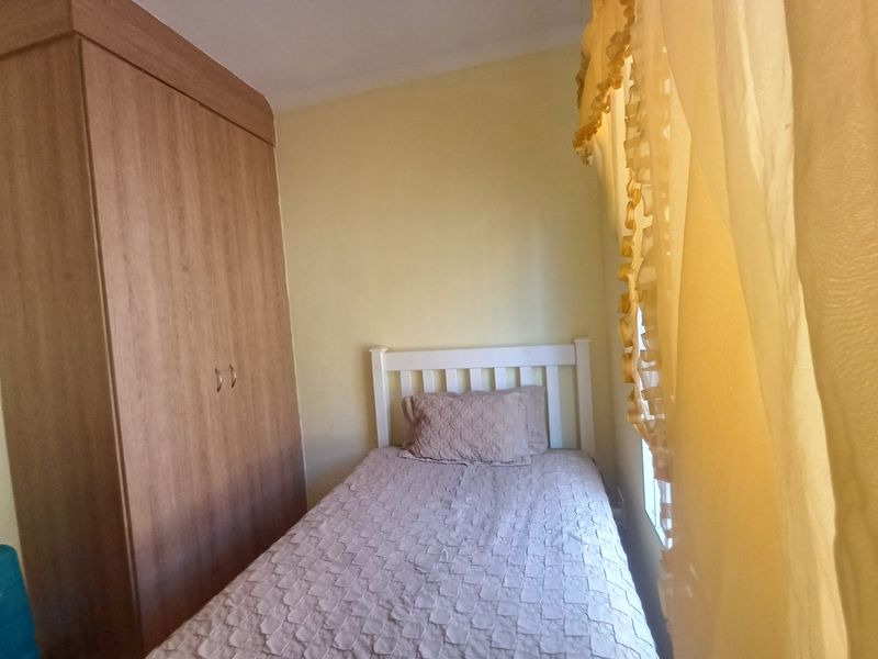 A compact bedroom featuring a built-in wooden wardrobe and neutral wall finishes.