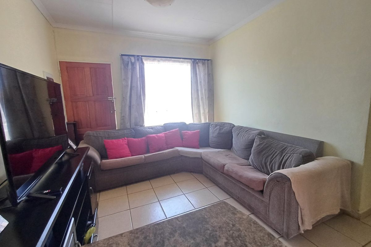 A functional living room featuring tiled flooring and a coved ceiling, providing a neutral base for potential interior updates.