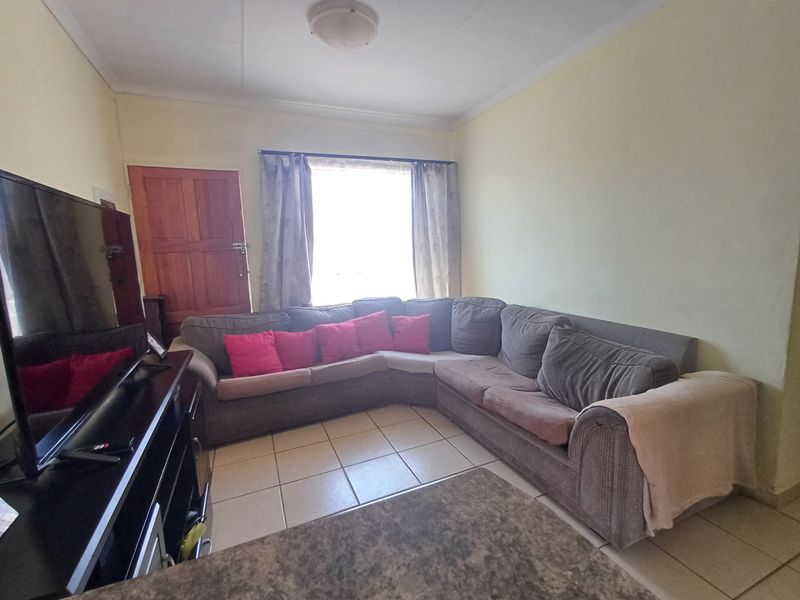 A functional living room featuring tiled flooring and a coved ceiling, providing a neutral base for potential interior updates.
