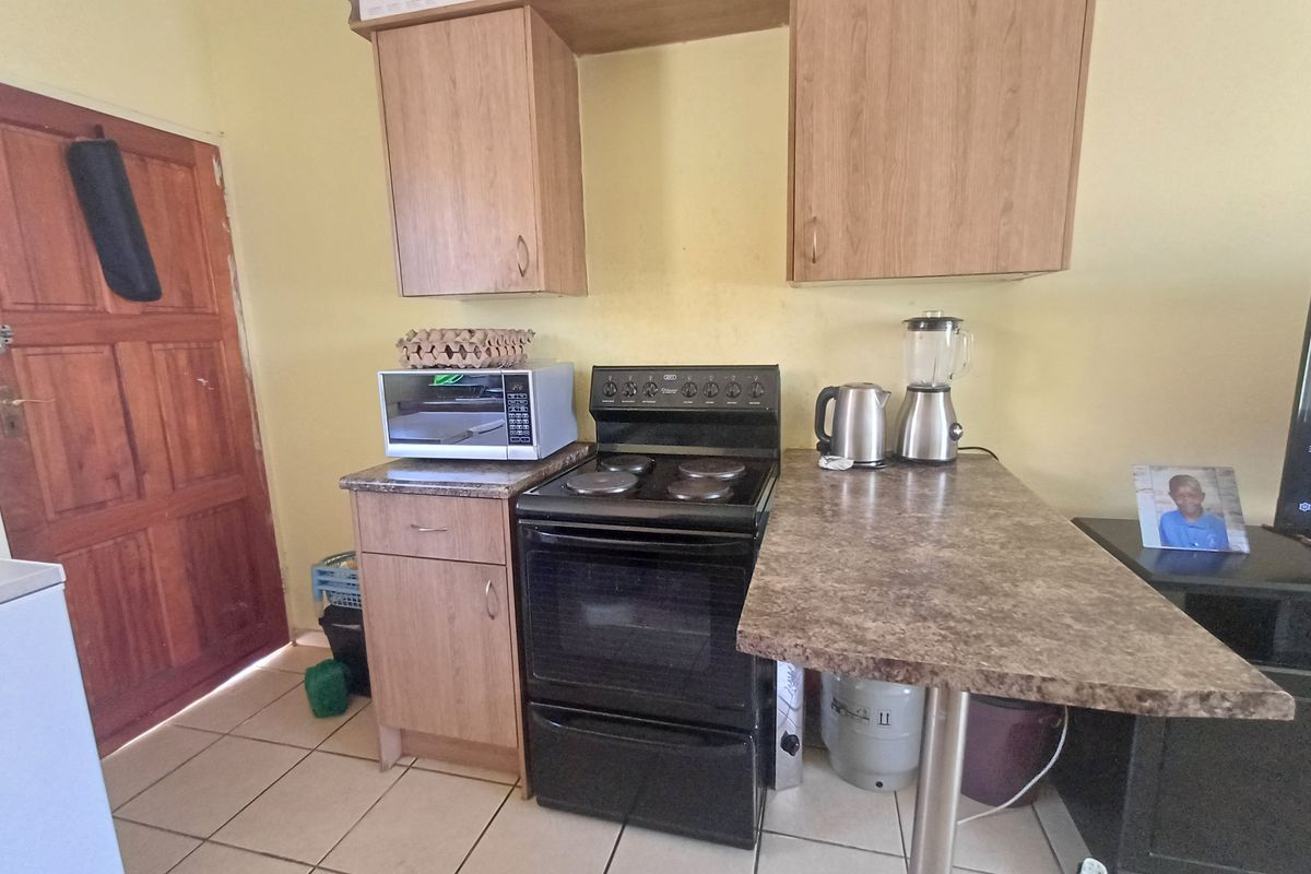 Compact kitchen area featuring laminate cabinetry, a freestanding stove, and tiled flooring, providing a functional space for meal preparation.