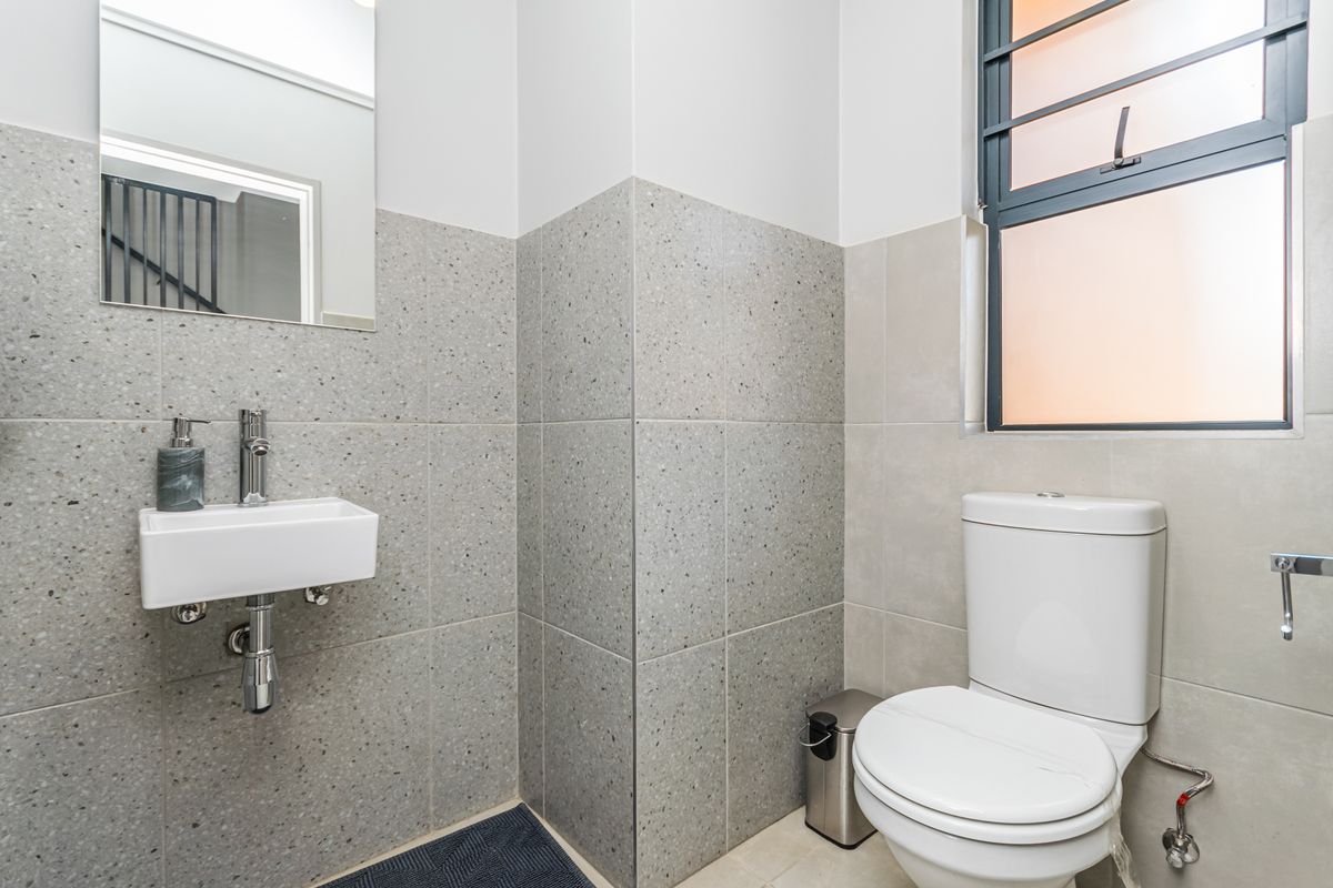 A modern guest bathroom featuring contemporary grey terrazzo-style wall tiling, a wall-mounted basin, and a sleek toilet suite.