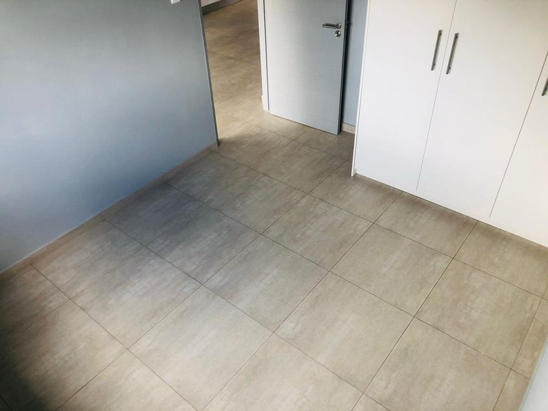 A clean, empty bedroom featuring neutral tiled flooring and modern built-in cupboards, offering a versatile space ready for personalization.