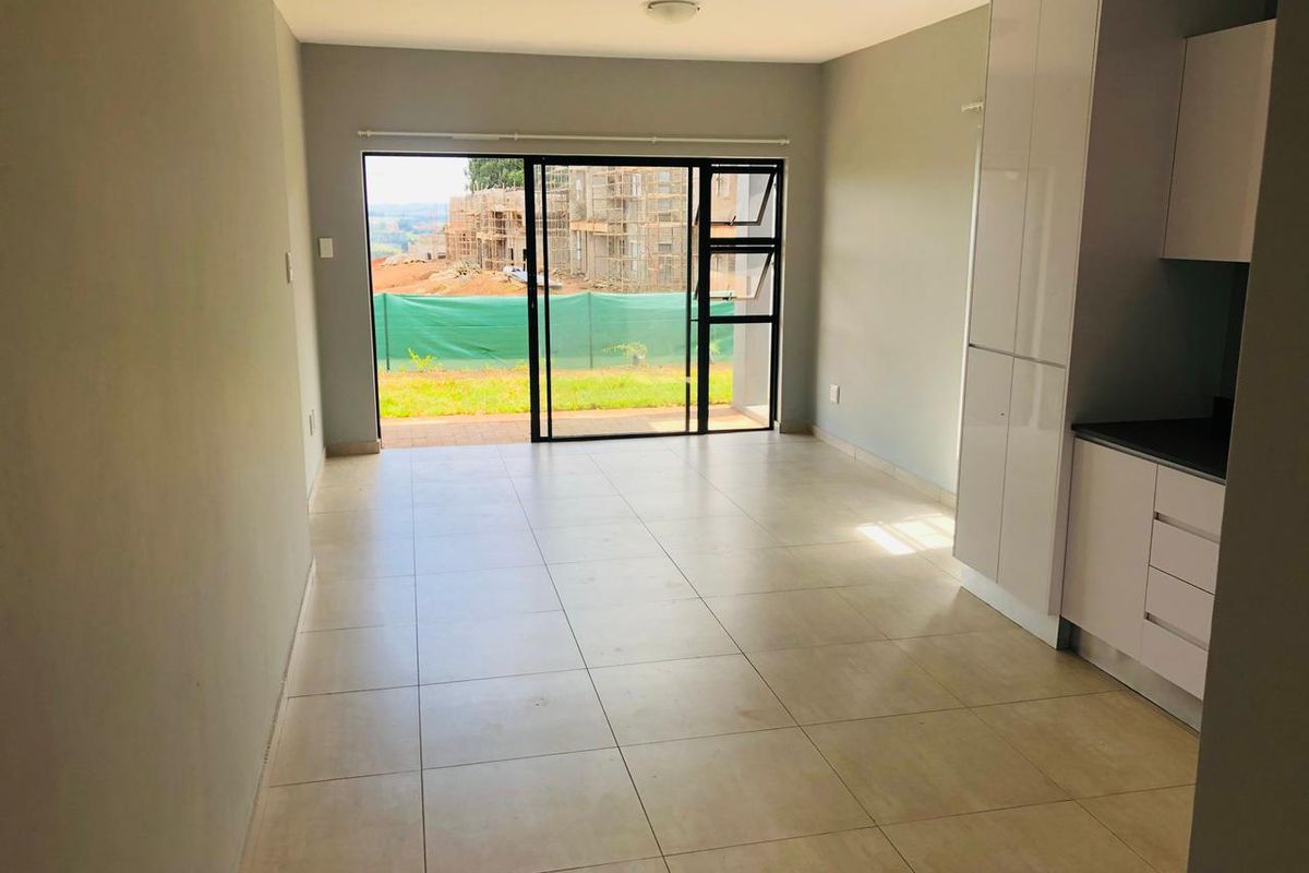 An open-plan living and kitchen area featuring tiled flooring, modern cabinetry, and a large sliding glass door leading to an outdoor space.